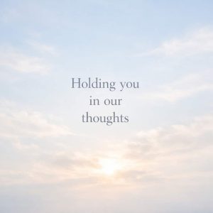 holding you in our thoughts sympathy message on soft sky with clouds background
